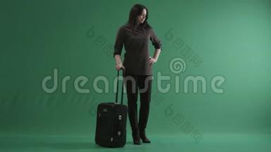 美丽的黑发女人站在她的手提箱旁边